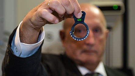 Optometrist holding a retinoscope dial wheel up to the light during a standard sight test